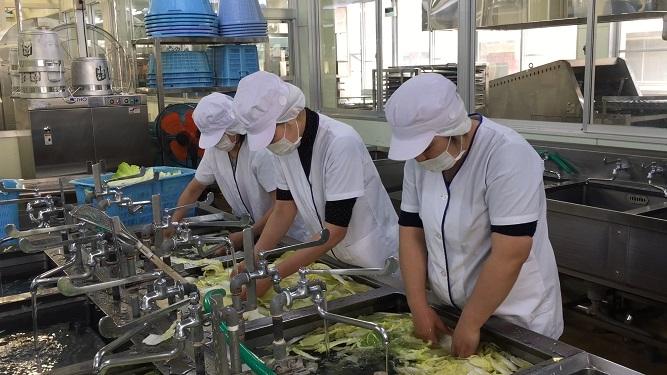 3人の白衣の調理員が食材を洗浄している多良木町学校給食センターの内部写真