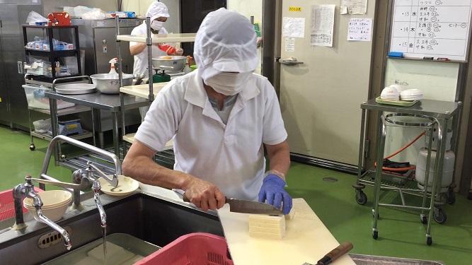 白衣の調理員が食材を切っている場面を写した多良木町学校給食センターの内部写真